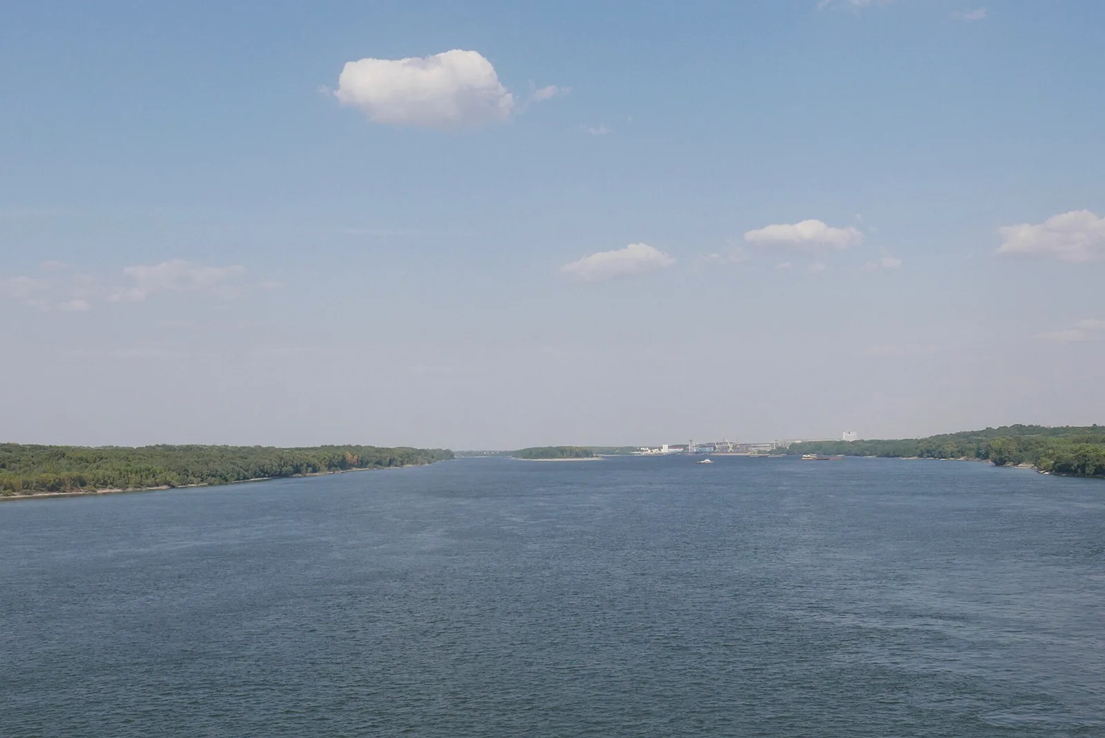 The Danube seen from the Friendship Bridge between Giurgiu and Ruse, wide grey water with wooded banks and a barge, the crossing every Bucharest to Sofia traveller makes